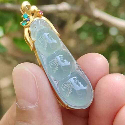 a hand holding a blue and green stone pendant