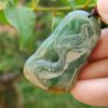 a hand holding a green and yellow stone