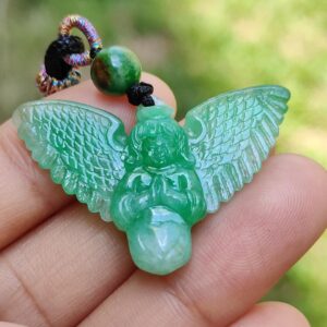 a hand holding a green angel pendant