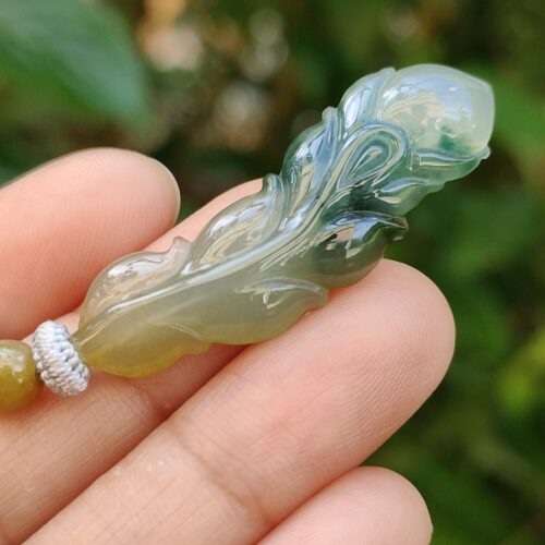 một bàn tay cầm một mặt dây chuyền ngọc bích
