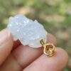 a hand holding a carved white jade pendant