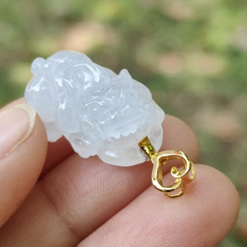 a hand holding a carved white jade pendant