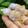 a hand holding a small white and yellow animal shaped necklace