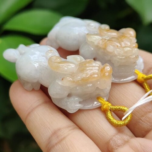 a hand holding a small white and yellow animal shaped necklace