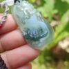 a hand holding a jade pendant