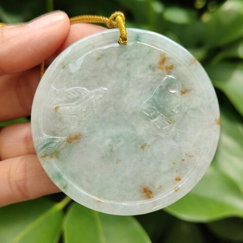 a hand holding a jade pendant