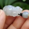 a hand holding a jade pendant