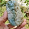 a hand holding a jade pendant