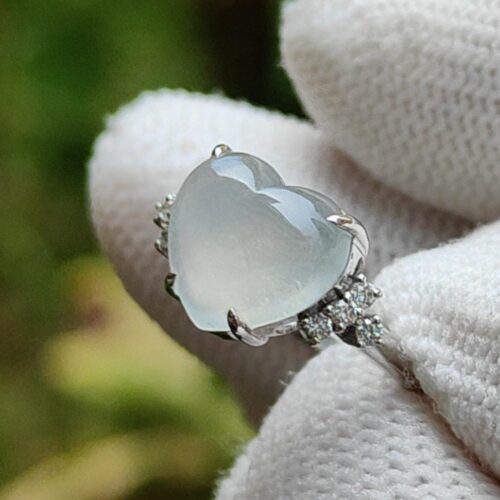 a hand wearing a white glove with a ring in the shape of a heart