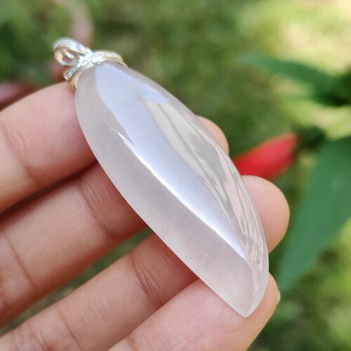 một bàn tay cầm một mặt dây chuyền đá trắng