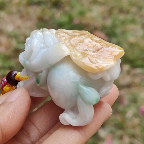 a hand holding a small white and yellow stone statue