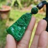 a hand holding a green pendant