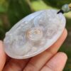 a hand holding a jade pendant