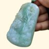 a hand holding a jade pendant