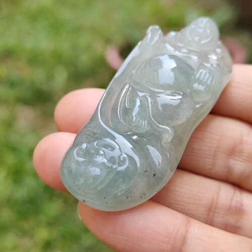 une main tenant un objet en jade