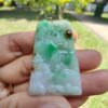 a hand holding a jade pendant