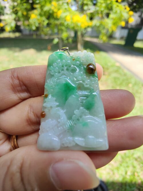 a hand holding a jade pendant