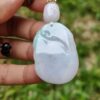a hand holding a jade pendant