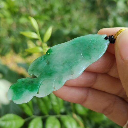 một bàn tay cầm một mặt dây chuyền ngọc bích