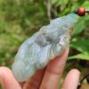 Una mano sosteniendo un colgante de jade.
