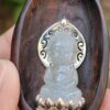 a hand holding a carved wooden spoon with a carved stone statue
