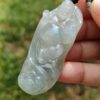 une main tenant un pendentif en jade