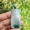 a hand holding a jade pendant