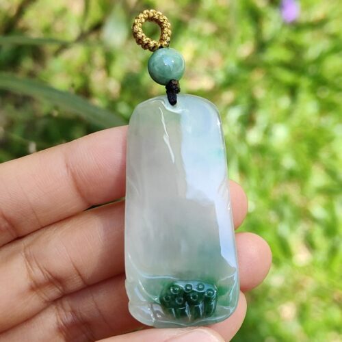 a hand holding a jade pendant