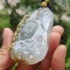 a hand holding a jade pendant