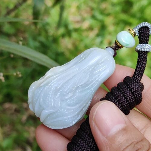 ஜேட் பதக்கத்தை வைத்திருக்கும் ஒரு கை