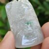 a hand holding a jade pendant