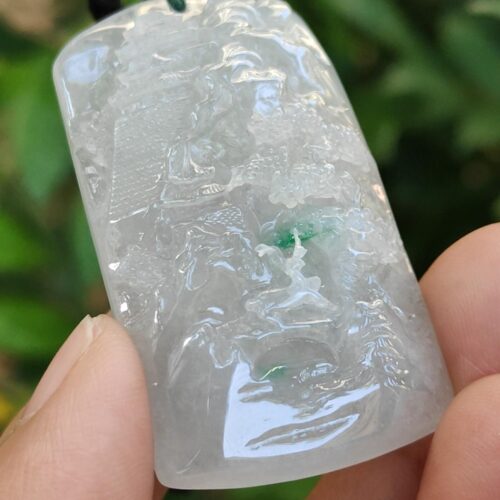a hand holding a jade pendant