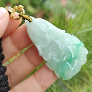 a hand holding a jade pendant