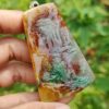 Una mano sosteniendo un colgante de piedra.