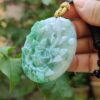 a hand holding a jade pendant