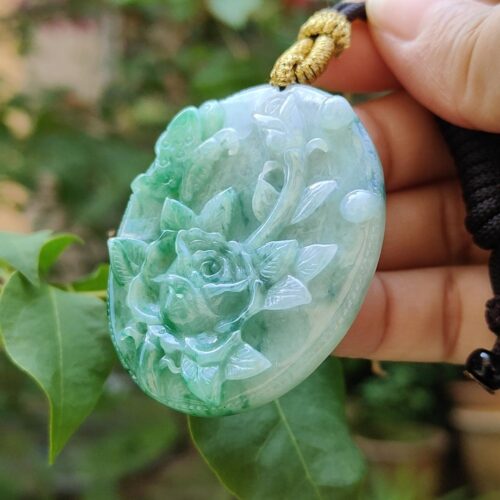 a hand holding a jade pendant