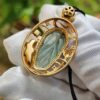 a gold pendant with a blue stone in it