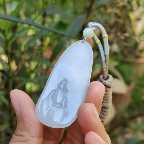 a hand holding a jade pendant