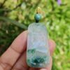 a hand holding a jade pendant