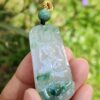 a hand holding a jade pendant