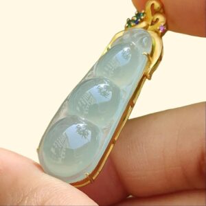a hand holding a gold ring with a blue stone in it