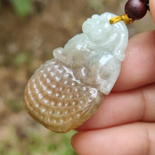 une main tenant un pendentif en jade