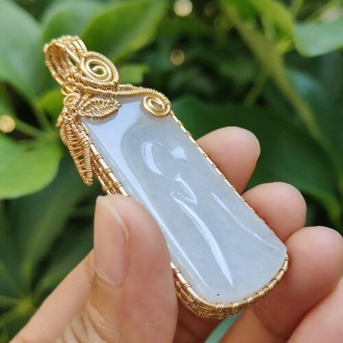 एक हाथ में जेड पेंडेंट थामे हुए