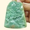 a hand holding a jade pendant