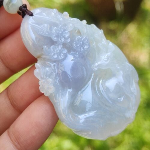 a hand holding a jade pendant