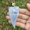 a hand holding a jade pendant