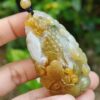 une main tenant un pendentif en jade
