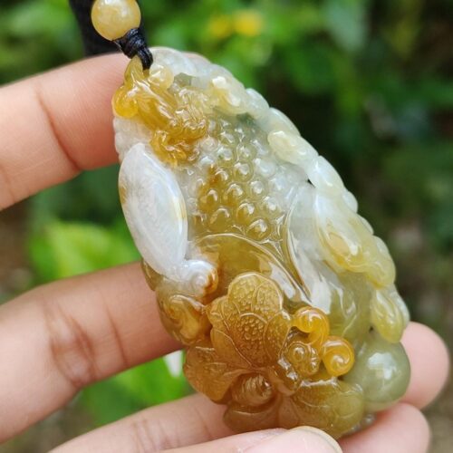 une main tenant un pendentif en jade