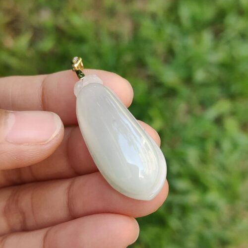 Una mano sosteniendo un colgante de piedra blanca.