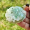 a hand holding a jade pendant
